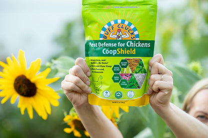 CoopShield Diatomaceous Earth Peppermint and herbs natural pest control for chickens held in front of sunflowers in the background