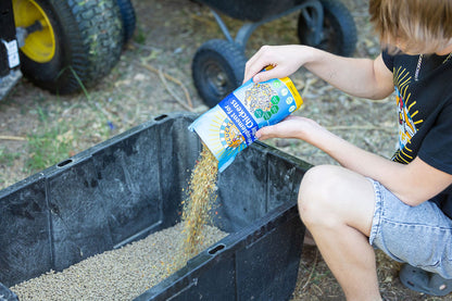 boy pouring buff clucks herb supplement in chicken layer feed